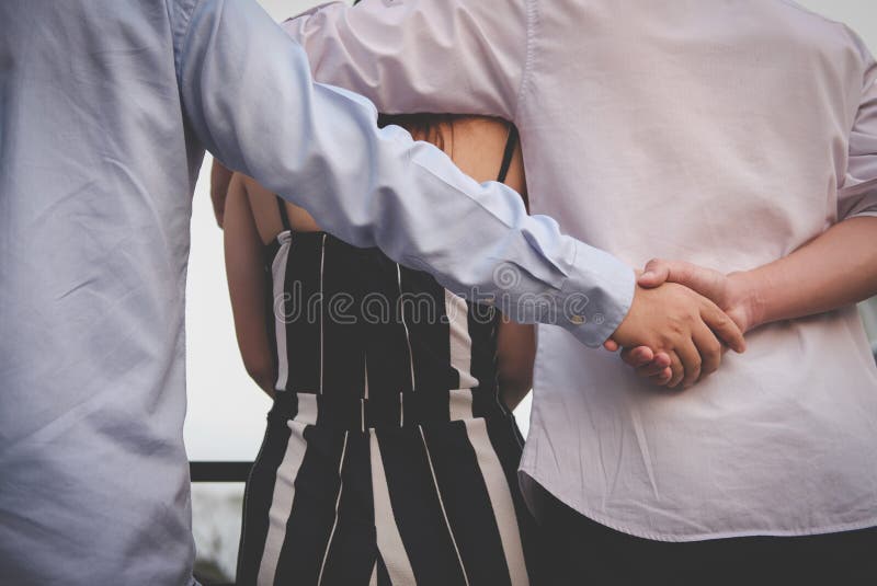 Donna omosessuale dell'abbraccio dell'uomo mentre tenendosi per mano con l'amante segreto fotografia stock