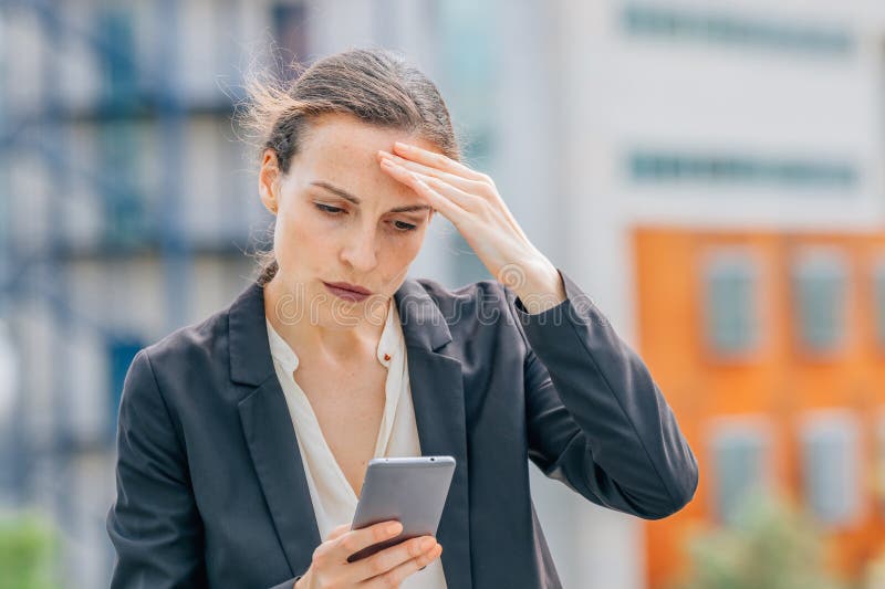 Donna per strada preoccupata di guardare il cellulare fotografie stock