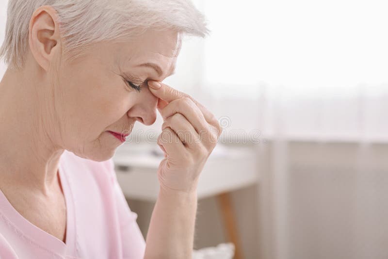 Donna senior affaticata che massaggia il ponte del naso, astenopia ritenente fotografia stock Donna senior affaticata che massaggia il ponte del naso, astenopia ritenente fotografia stock