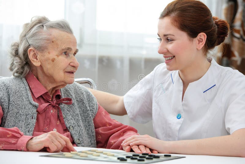 Senior women playing checkers with a nurse in a retirement home. Senior women playing checkers with a nurse in a retirement home