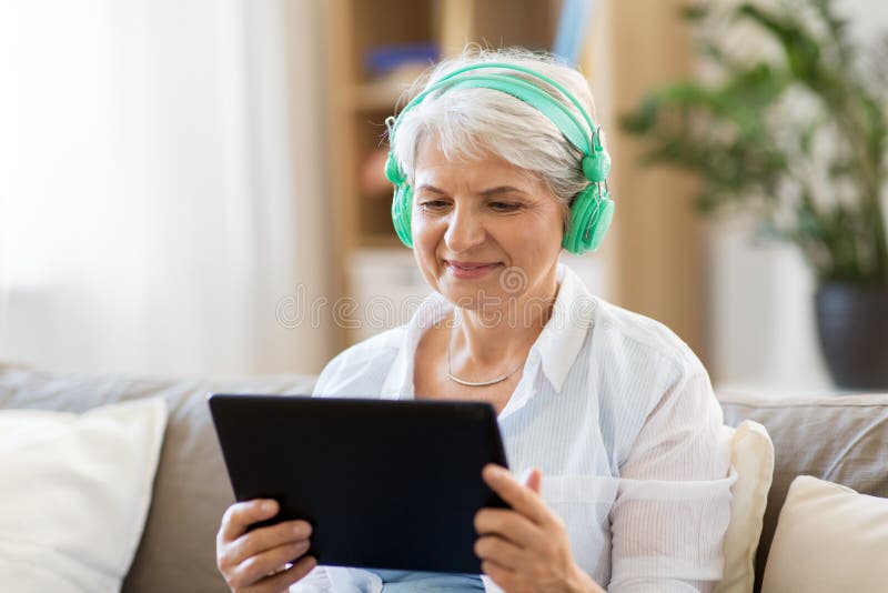 Donna senior in cuffie che ascolta la musica fotografia stock Donna senior in cuffie che ascolta la musica fotografia stock