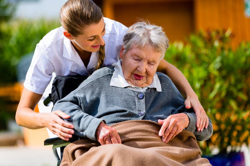 Senior women in nursing home with nurse in garden sitting in wheelchair. Senior women in nursing home with nurse in garden sitting in wheelchair