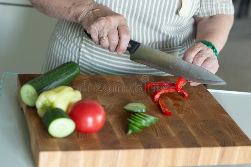 Senior or older woman cooking salad in kitchen. Healthy food concept. Healthy lifestyle.Grandmother prepares a healthy meal for her grandchildren. Senior or older woman cooking salad in kitchen. Healthy food concept. Healthy lifestyle.Grandmother prepares a healthy meal for her grandchildren