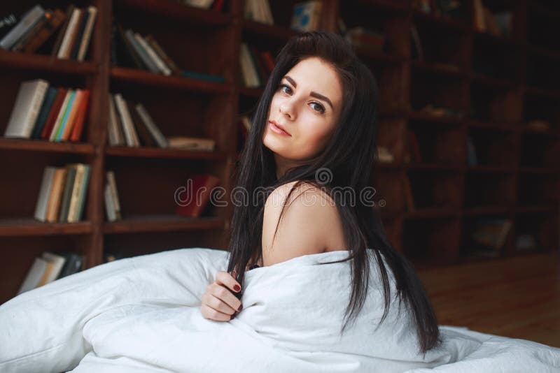 Donna sensuale con capelli scuri che si siedono su un letto fotografia stock libera da diritti Donna sensuale con capelli scuri che si siedono su un letto fotografia stock libera da diritti