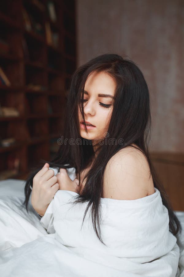 Donna sensuale con capelli scuri che si siedono su un letto fotografie stock libere da diritti Donna sensuale con capelli scuri che si siedono su un letto fotografie stock libere da diritti