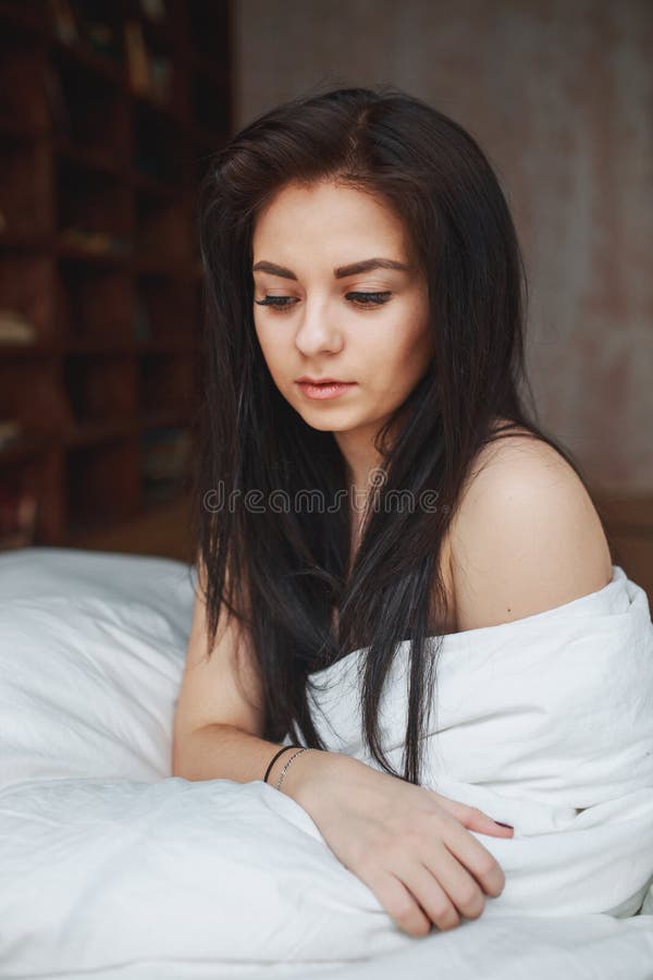 Donna sensuale con capelli scuri che si siedono su un letto immagini stock libere da diritti Donna sensuale con capelli scuri che si siedono su un letto immagini stock libere da diritti
