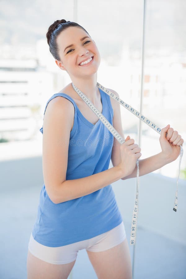 Donna snella allegra in nastro di misurazione della tenuta degli abiti sportivi fotografia stock libera da diritti Donna snella allegra in nastro di misurazione della tenuta degli abiti sportivi fotografia stock libera da diritti