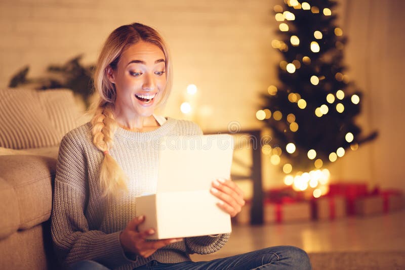 Donna sorpresa apre una scatola regalo magica di Natale fotografia stock