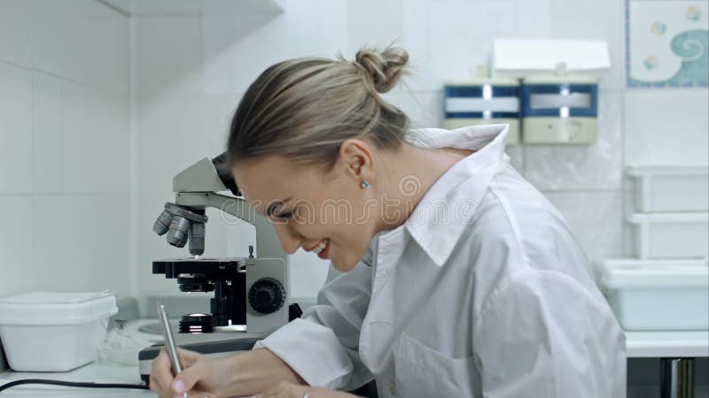 Donna sorpresa che lavora con un microscopio in laboratorio