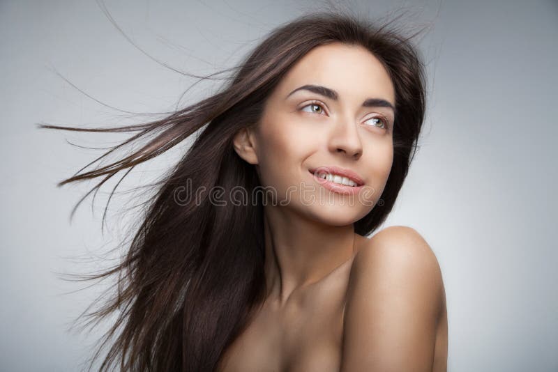 Donna sorridente attraente con capelli lunghi su grey immagini stock libere da diritti Donna sorridente attraente con capelli lunghi su grey immagini stock libere da diritti