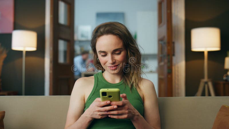 Donna sorridente che invia messaggi al salotto del telefono ingrandisce. donna che chiacchiera col cellulare