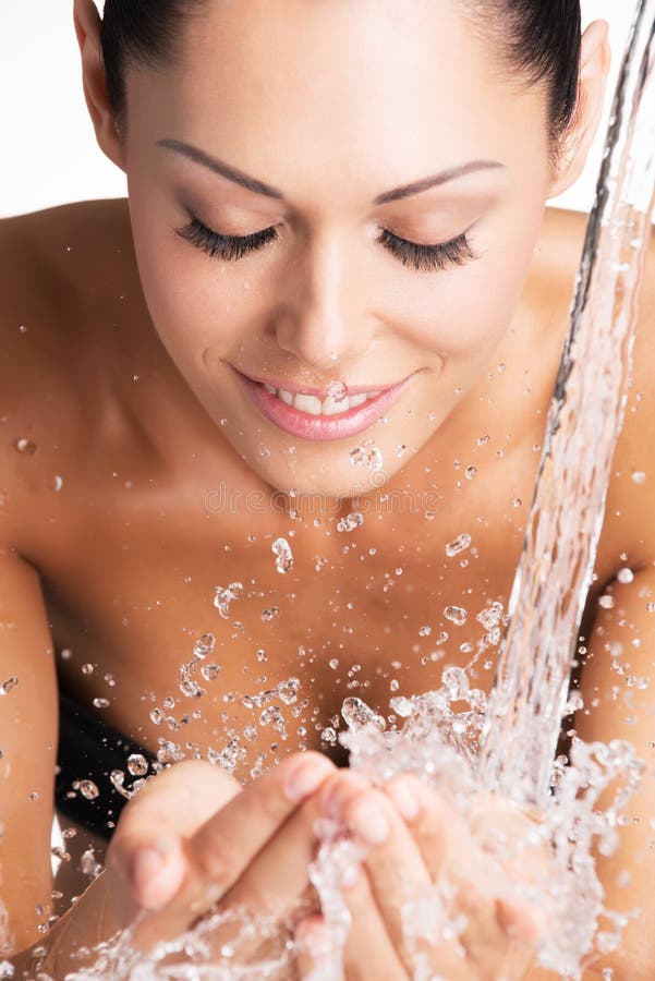 Closeup portrait of a smiling woman washing her clean face with water. Closeup portrait of a smiling woman washing her clean face with water