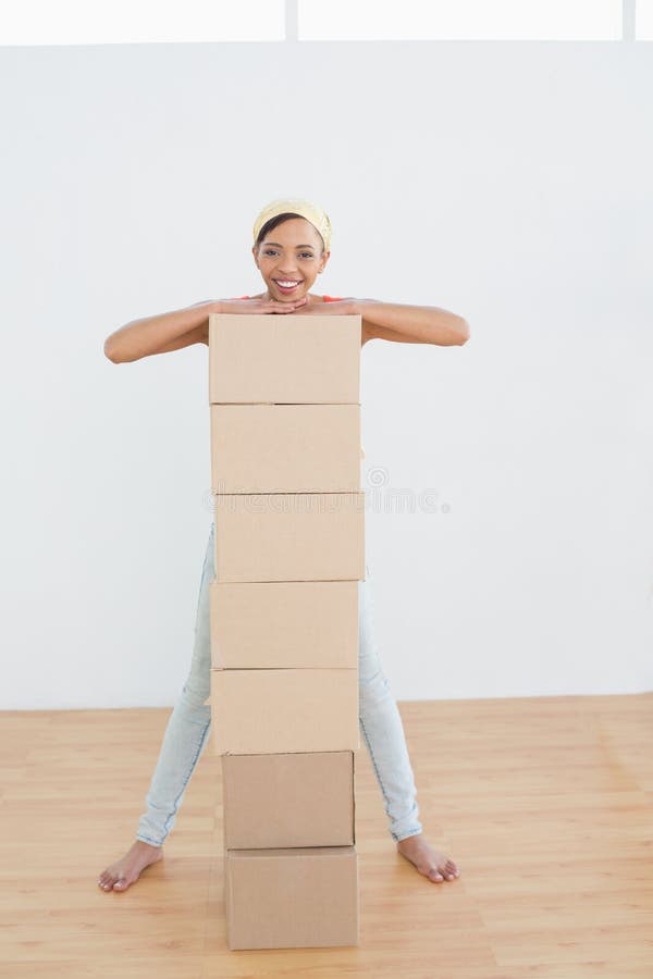 Donna sorridente che si muove nella nuova casa con una pila di scatole fotografie stock libere da diritti