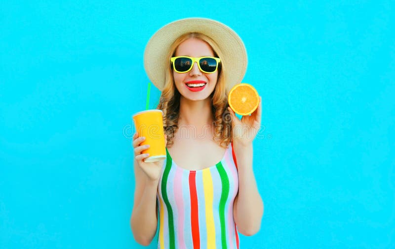 Donna sorridente felice del ritratto di estate che tiene in sua tazza delle mani del succo di frutta, fetta di arancia in cappell fotografia stock libera da diritti Donna sorridente felice del ritratto di estate che tiene in sua tazza delle mani del succo di frutta, fetta di arancia in cappell fotografia stock libera da diritti