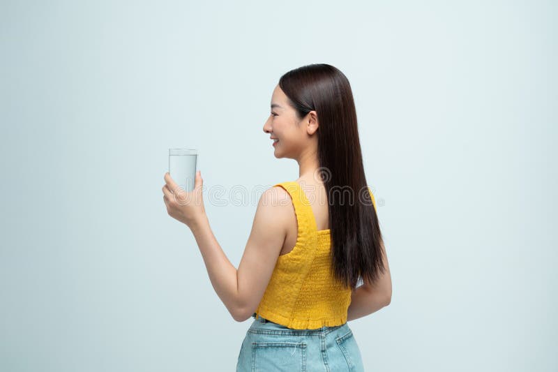 Donna sorridente felice, sana, con pelle sana, che beve acqua pura e guarda indietro fotografia stock libera da diritti