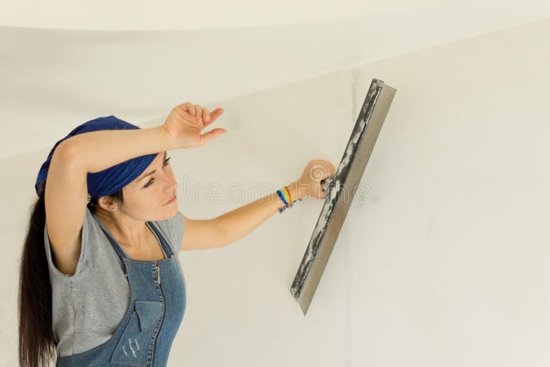 Donna stanca che wallpapering una parete immagine stock Donna stanca che wallpapering una parete immagine stock