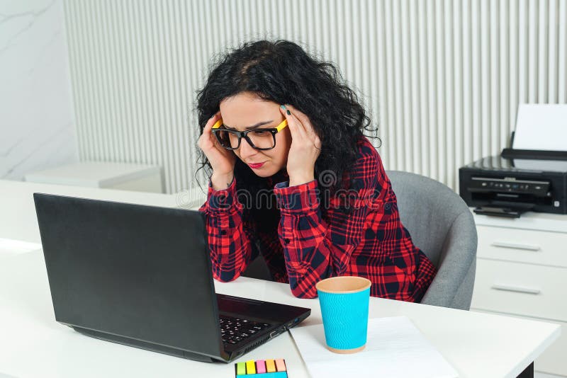 Donna stanca di affari nel luogo di lavoro Donna sollecitata che lavora al computer portatile in ufficio moderno Mano della holdi fotografia stock libera da diritti Donna stanca di affari nel luogo di lavoro Donna sollecitata che lavora al computer portatile in ufficio moderno Mano della holdi fotografia stock libera da diritti