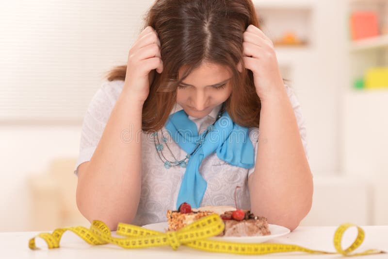 Depressed dieting woman with cake and measuring tape. Depressed dieting woman with cake and measuring tape