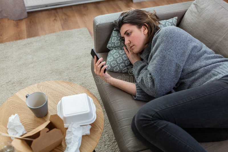 mental health, psychological help and depression concept - stressed woman with smartphone lying on sofa at home. mental health, psychological help and depression concept - stressed woman with smartphone lying on sofa at home