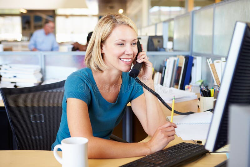 Donna sul telefono in ufficio moderno occupato fotografie stock Donna sul telefono in ufficio moderno occupato fotografie stock