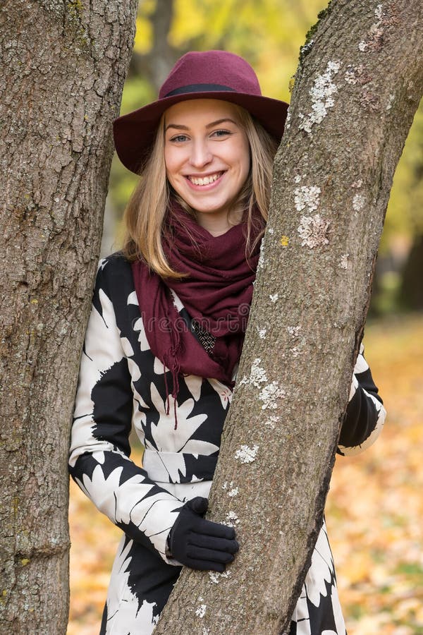 Donna in un cappello modellato floreale di rosso di vino e del cappotto nel parco, dal fiume Ragazza felice, ritratto variopinto fotografia stock Donna in un cappello modellato floreale di rosso di vino e del cappotto nel parco, dal fiume Ragazza felice, ritratto variopinto fotografia stock