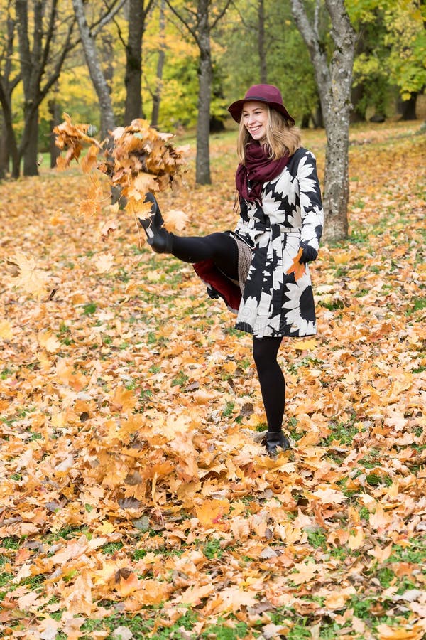 Donna in un cappello modellato floreale di rosso di vino e del cappotto nel parco, dal fiume Ragazza felice, ritratto variopinto fotografia stock libera da diritti Donna in un cappello modellato floreale di rosso di vino e del cappotto nel parco, dal fiume Ragazza felice, ritratto variopinto fotografia stock libera da diritti