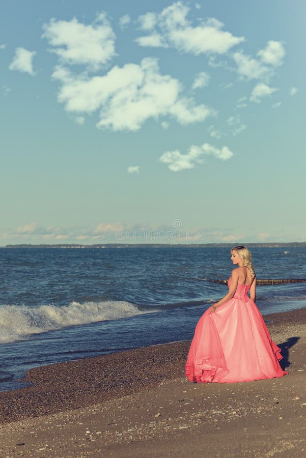 Donna in vestito da sera rosso di Tulle dall'oceano fotografia stock Donna in vestito da sera rosso di Tulle dall'oceano fotografia stock