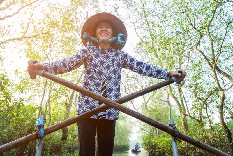Donna vietnamita che rema barca di legno sul fiume fotografia stock libera da diritti Donna vietnamita che rema barca di legno sul fiume fotografia stock libera da diritti