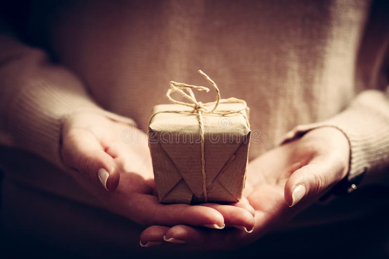 Donnant un cadeau, présent fait main enveloppé en papier