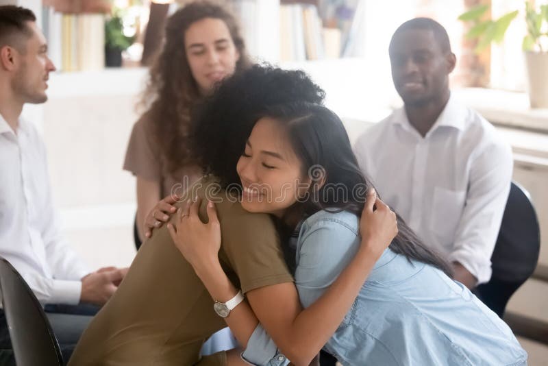Donne asiatiche ed africane che abbracciano dando supporto psicologico durante la terapia