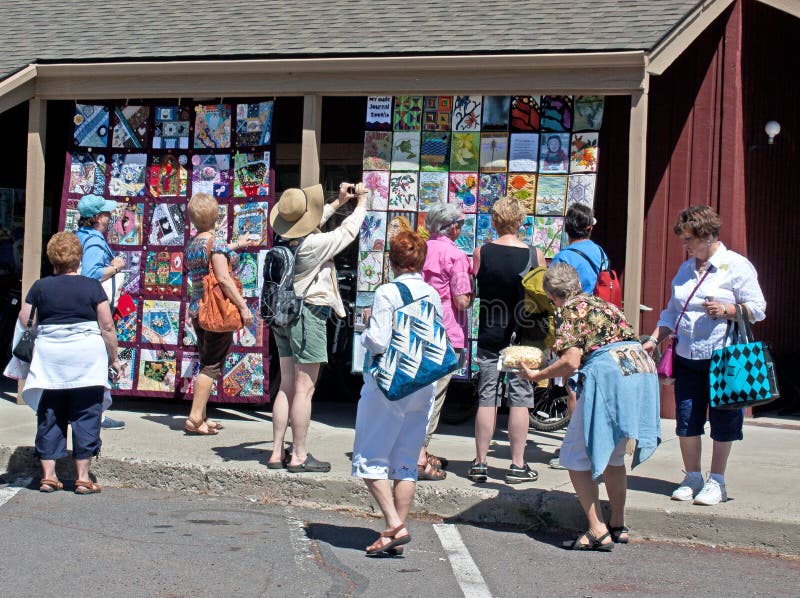 Women enjoying and photographing quilts hanging on a building at the 2011 outdoor quilt show in Sisters, Oregon. Women enjoying and photographing quilts hanging on a building at the 2011 outdoor quilt show in Sisters, Oregon