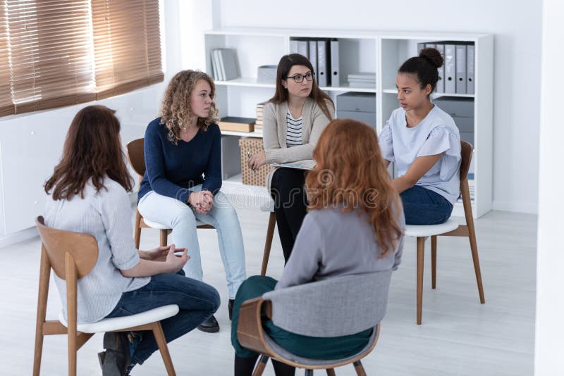 Donne che si sostengono nel corso della riunione dei gruppi di psicoterapia immagini stock Donne che si sostengono nel corso della riunione dei gruppi di psicoterapia immagini stock