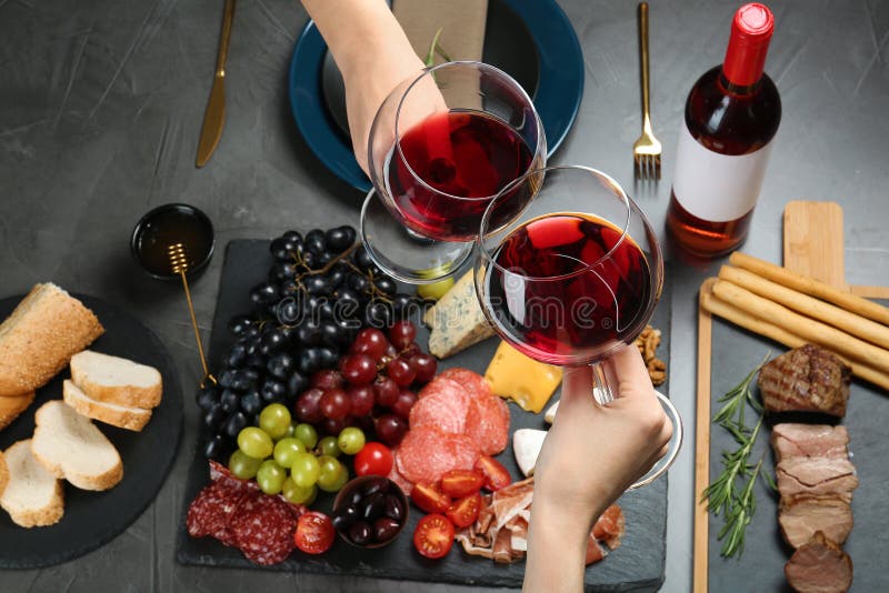 Donne che tengono i vetri di vino rosso sopra la tavola con gli spuntini fotografia stock libera da diritti Donne che tengono i vetri di vino rosso sopra la tavola con gli spuntini fotografia stock libera da diritti
