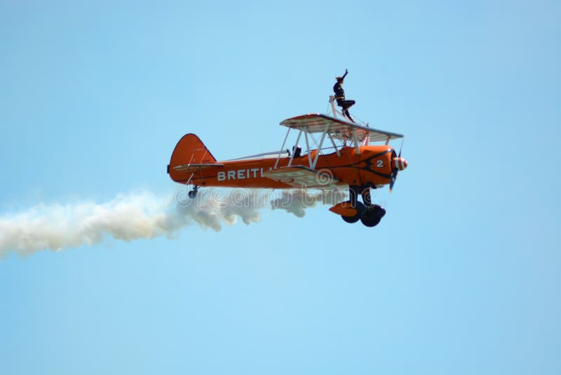 A female member of the Breitling wing walker team waves to the crowd below after finishing a display. A female member of the Breitling wing walker team waves to the crowd below after finishing a display