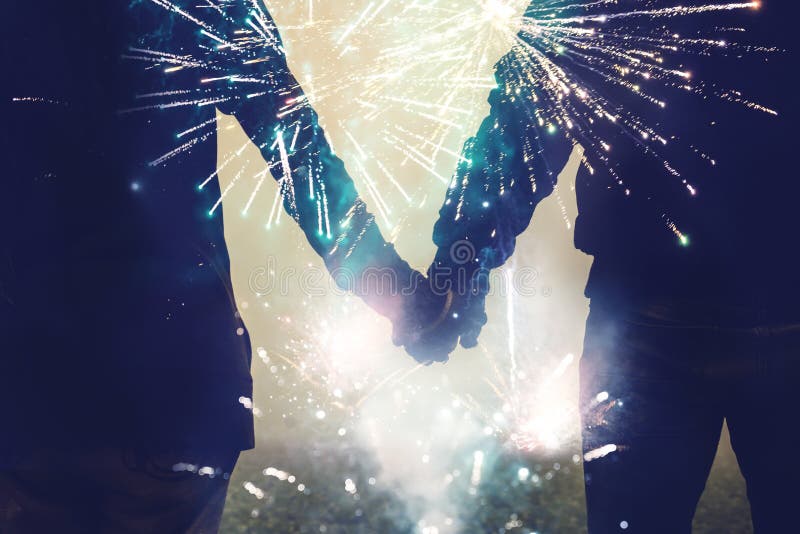 Donne dell'amante ed asiatici degli uomini Le mani di scossa del supporto guardano i fuochi d'artificio fotografia stock libera da diritti