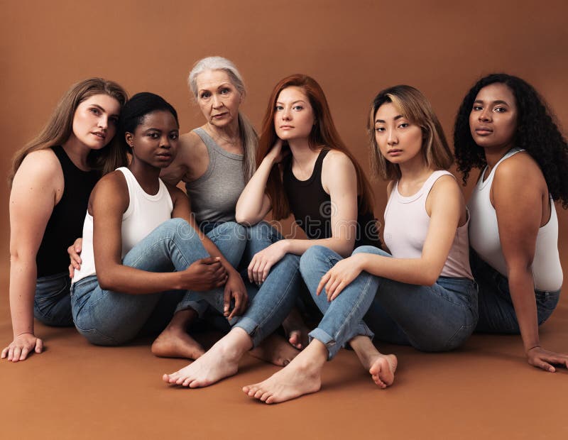 Donne diverse in casual sedute su fondo marrone. gruppo multietnico di donne che guardano le telecamere in studio