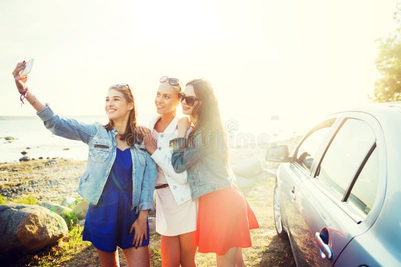 Donne felici che prendono selfie vicino all'automobile alla spiaggia