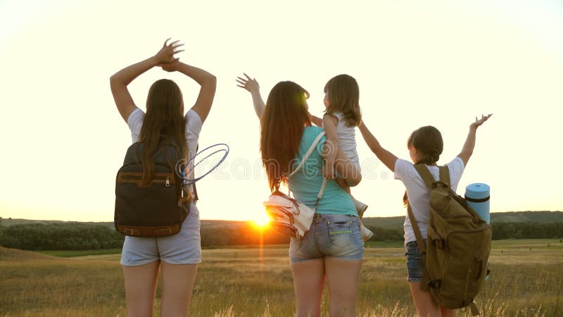 Donne libere viaggiano con zainetti che agitano le mani e approfittano del tramonto. l'avventura e il concetto di viaggio. madre s stock footage