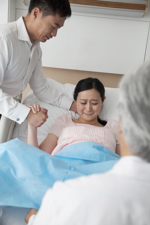 Donne nel lavoro che tiene la sua mano dei mariti con medico nella priorità alta nell'ospedale fotografie stock Donne nel lavoro che tiene la sua mano dei mariti con medico nella priorità alta nell'ospedale fotografie stock