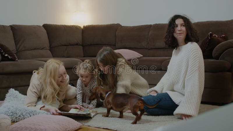Donne ragazze leggono libri e si divertono con i cani sul pavimento in camera di riposo. video d archivio