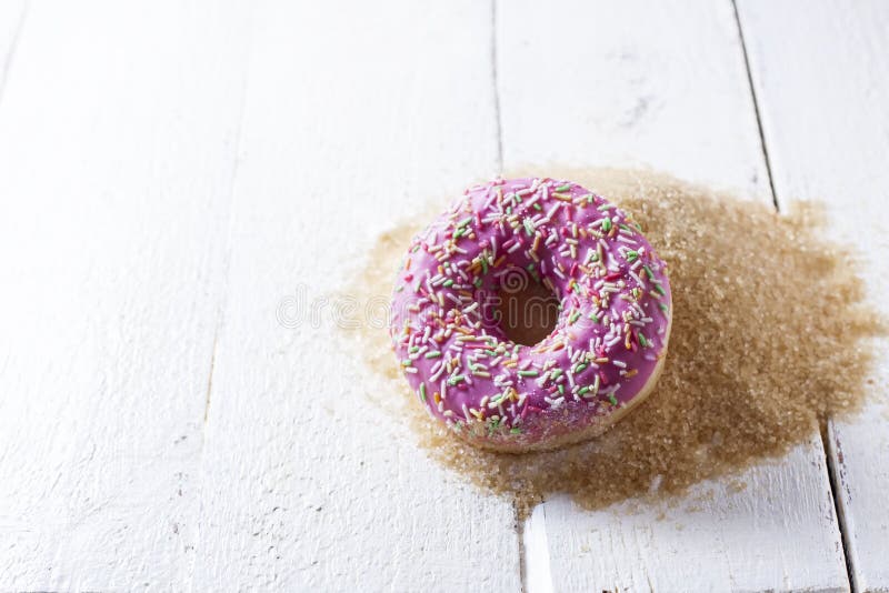 Donut con hielo rosa sobre una montaña de azúcar Comida chatarra en una vieja mesa blanca de madera con espacio para copiar fotos de archivo Donut con hielo rosa sobre una montaña de azúcar Comida chatarra en una vieja mesa blanca de madera con espacio para copiar fotos de archivo