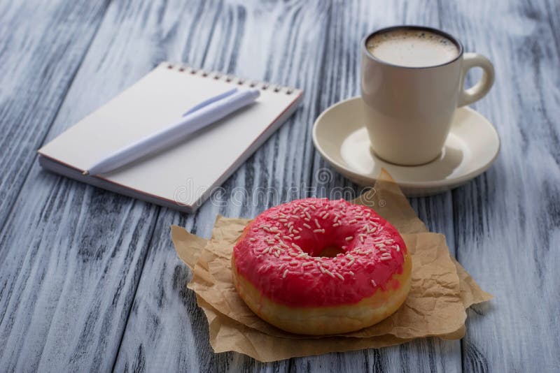 Donut, cup of coffee and notebook