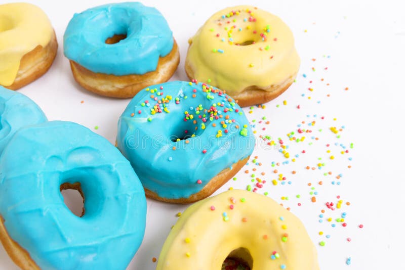 Donuts med blå och gul glasyr på en vit bakgrund arkivfoto Donuts med blå och gul glasyr på en vit bakgrund arkivfoto