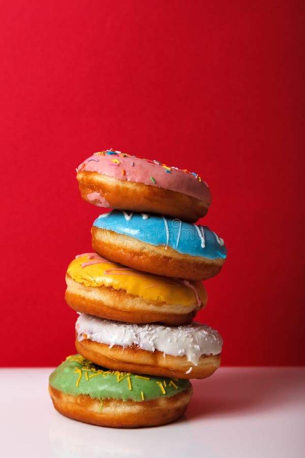 Donuts in Multi-colored Glaze Stacked on Top of Each Other on a Red ...