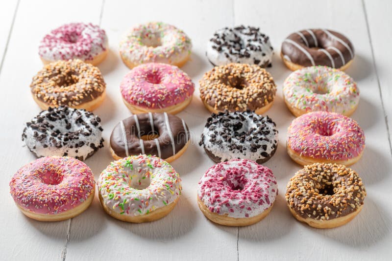 Donuts with Various Types of Toppings on White Table Stock Image