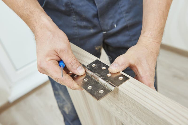 Close-up carpenter process of wood door hinge installation.