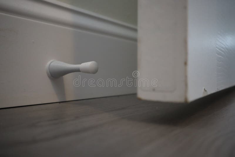 Door stop. Door spring stopper in a white house or office. Isolated door stop spring mounted on trim. hold doors open during, prot