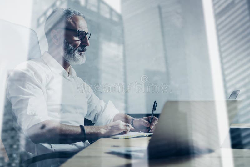 Doppelbelichtungskonzept Erwachsener bärtiger Geschäftsmann, der am hölzernen Tisch im modernen Platz arbeitet Eleganter Mann, de lizenzfreie stockbilder Doppelbelichtungskonzept Erwachsener bärtiger Geschäftsmann, der am hölzernen Tisch im modernen Platz arbeitet Eleganter Mann, de lizenzfreie stockbilder