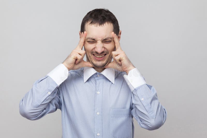 Dor da dor de cabeça Retrato do homem de negócios irritado da cerda na posição azul clássica da camisa que guarda sua cabeça dolo fotografia de stock royalty free Dor da dor de cabeça Retrato do homem de negócios irritado da cerda na posição azul clássica da camisa que guarda sua cabeça dolo fotografia de stock royalty free