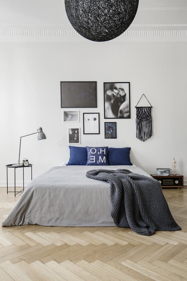 Dormitorio con la cama gigante con las almohadas azules, el edredón gris y la manta, galería de las ilustraciones enmarcadas en l imagen de archivo libre de regalías Dormitorio con la cama gigante con las almohadas azules, el edredón gris y la manta, galería de las ilustraciones enmarcadas en l imagen de archivo libre de regalías